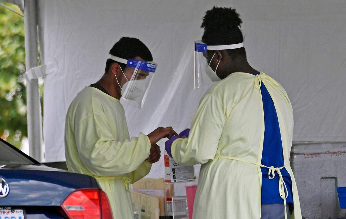 Medical personnel process a drive-thru COVID-19 test at StarMed Family & Urgent Care on Monday, July 20, 2020.