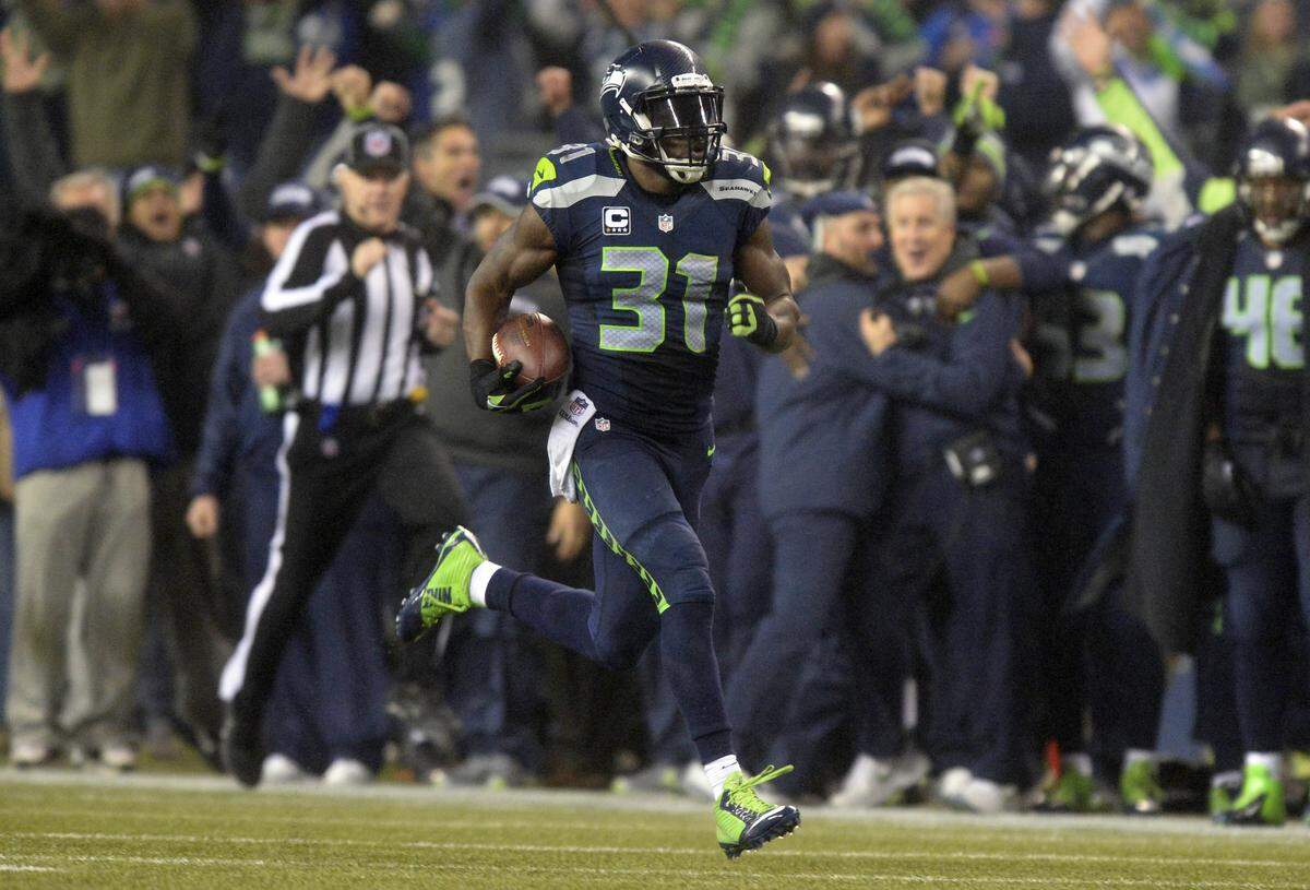 Seattle Seahawks safety Kam Chancellor (31) heads to the end zone for a pick-6 touchdown past Seahawks head coach Pete Carroll after intercepting a Cam Newton pass in a playoff game on Jan. 10, 2015. Seattle won 31-17.