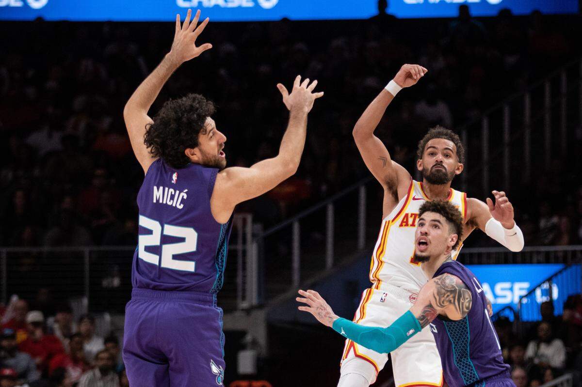 Atlanta Hawks guard Trae Young (11) makes a pass against Charlotte Hornets guard Vasilije Micic (22) and guard LaMelo Ball (1) during the fourth quarter at State Farm Arena.