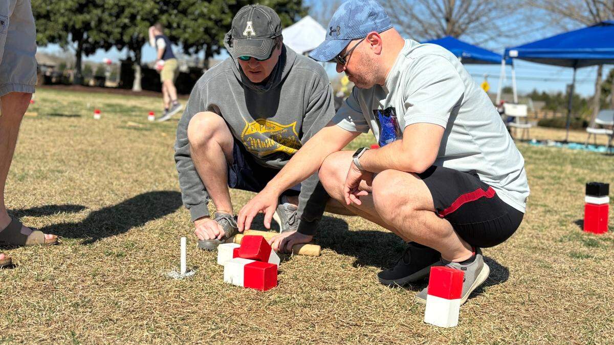 Dan Corey of Raleigh and Jeremy Reed of Maryland examine field kubbs at the North Carolina Kubb Tournament in March.