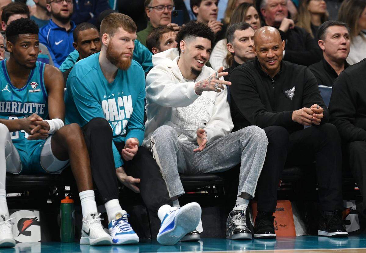 Injured Charlotte Hornets guard LaMelo Ball, center, smiles as he points out to the lane during first half action against the Milwaukee Bucks at Spectrum Center in Charlotte, NC on Thursday, February 29, 2024.