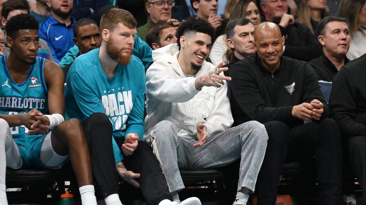 Injured Charlotte Hornets guard LaMelo Ball, center, smiles as he points out to the lane during first half action against the Milwaukee Bucks at Spectrum Center in Charlotte, NC on Thursday, February 29, 2024.