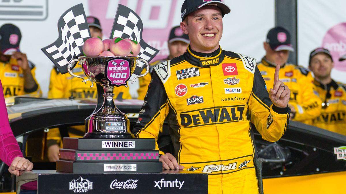 Feb 23, 2025; Hampton, Georgia, USA; Christopher Bell (20) poses with his trophy in Victory Lane after claiming a victory at Atlanta Motor Speedway.