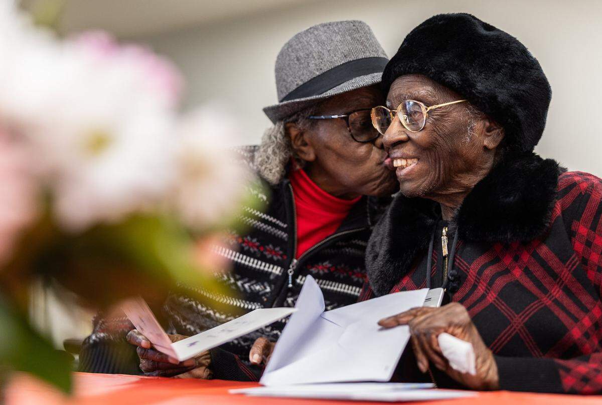 Julia Ann Teamer, right, gets a birthday kiss from her next door neighbor, Zedia Williams, during her 108th birthday celebration at her retirement community in Charlotte, N.C., on Thursday, January 16, 2025.