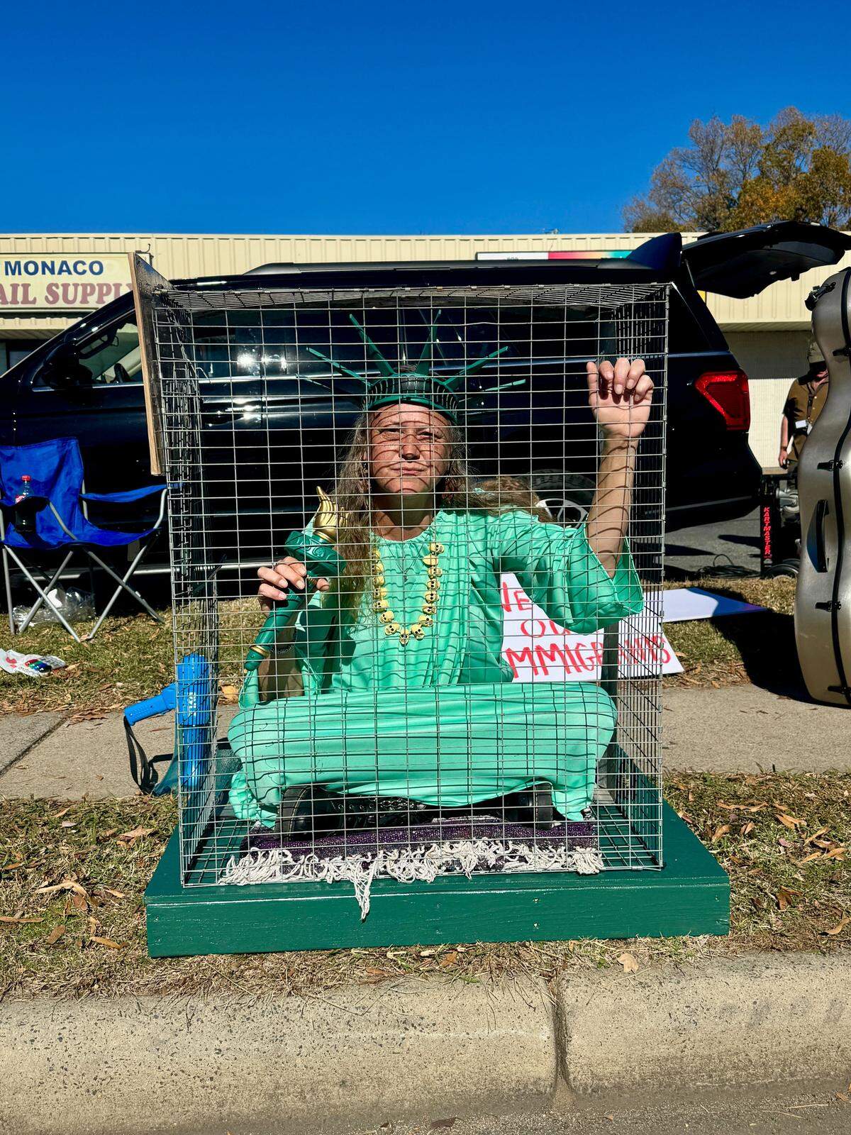Shana Blake sits in a cage in a small protest outside Manolo’s Bakery in east Charlotte on Monday, Nov. 17, 2025. The bakery closed for the first time in 28 years after Border Patrol arrests in Charlotte. A handful of protesters gathered outside the bakery to protest ICE activity in the neighborhood. “Even if [the bakery’s] not open, it’s such a faith effort to have people show up and support,” Blake said.