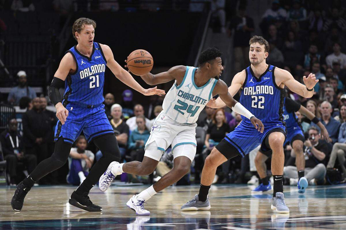 Charlotte Hornets forward Brandon Miller (24) drives past Orlando Magic center Moritz Wagner (21) and forward Franz Wagner (22) during the first half at the Spectrum Center.