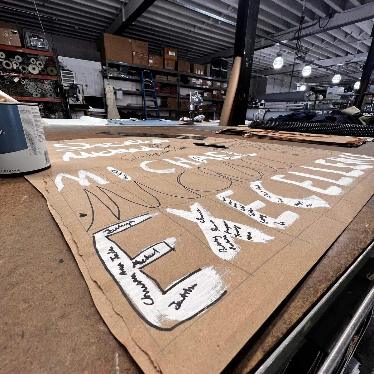 The process of Mike Jones designing the scarf of the month, celebrating Juneteenth. The scarf says “Excellence was once a dream,” in Jones’s handwriting.