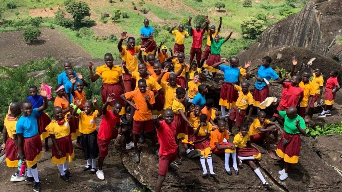 Children wave to the camera at Acres of Hope in Uganda.