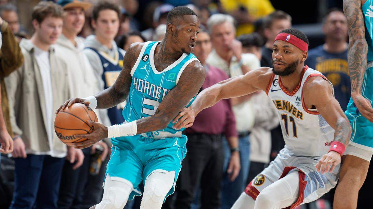 Charlotte Hornets guard Terry Rozier, left, looks to pass the ball as Denver Nuggets forward Bruce Brown defends in the first half of an NBA basketball game, Sunday, Dec. 18, 2022, in Denver. (AP Photo/David Zalubowski)