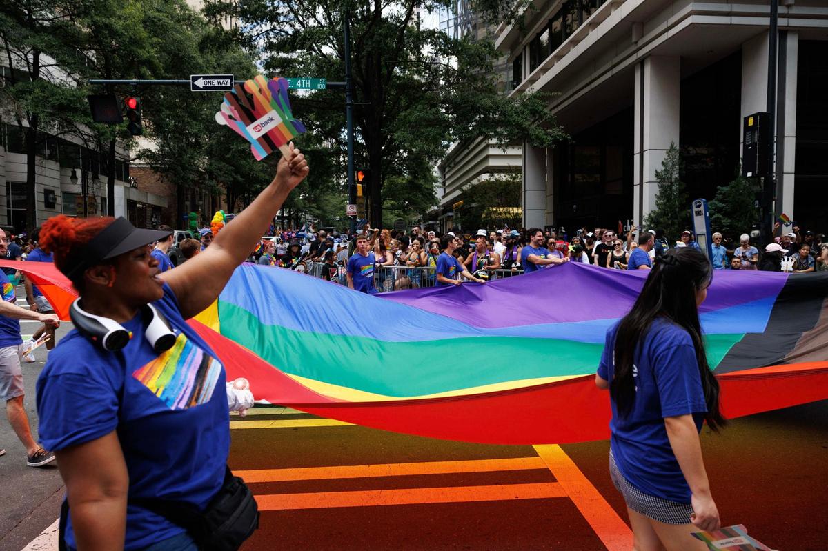 Participants from Queens University march down Fourth Street carrying a large Pride Flag during the Charlotte Pride Festival & Parade on Sunday, Aug. 18, 2024
