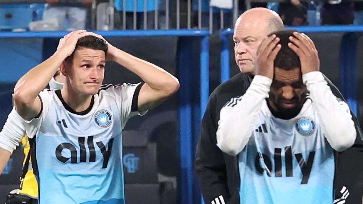 Charlotte FC central midfielder Ashley Westwood, left and right back Nathan Byrne, right, walk off the pitch with team owner David Tepper, back right, following the team’s 3-1 loss to New York City FC in Game 3 of the MLS Playoffs at Bank of America Stadium in Charlotte, NC on Friday, November 7, 2025.