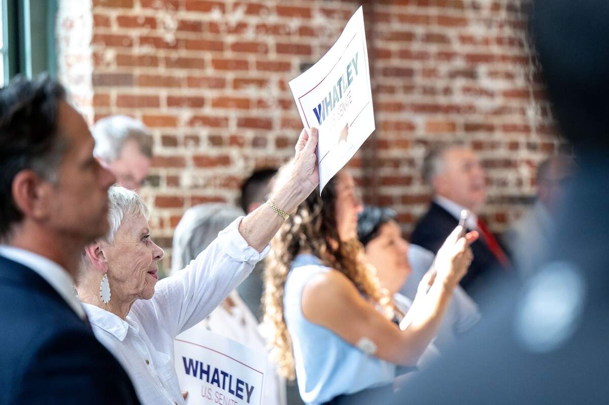 Attendees raise signs for Michael Whatley at Loray Mill in Gastonia Thursday.
