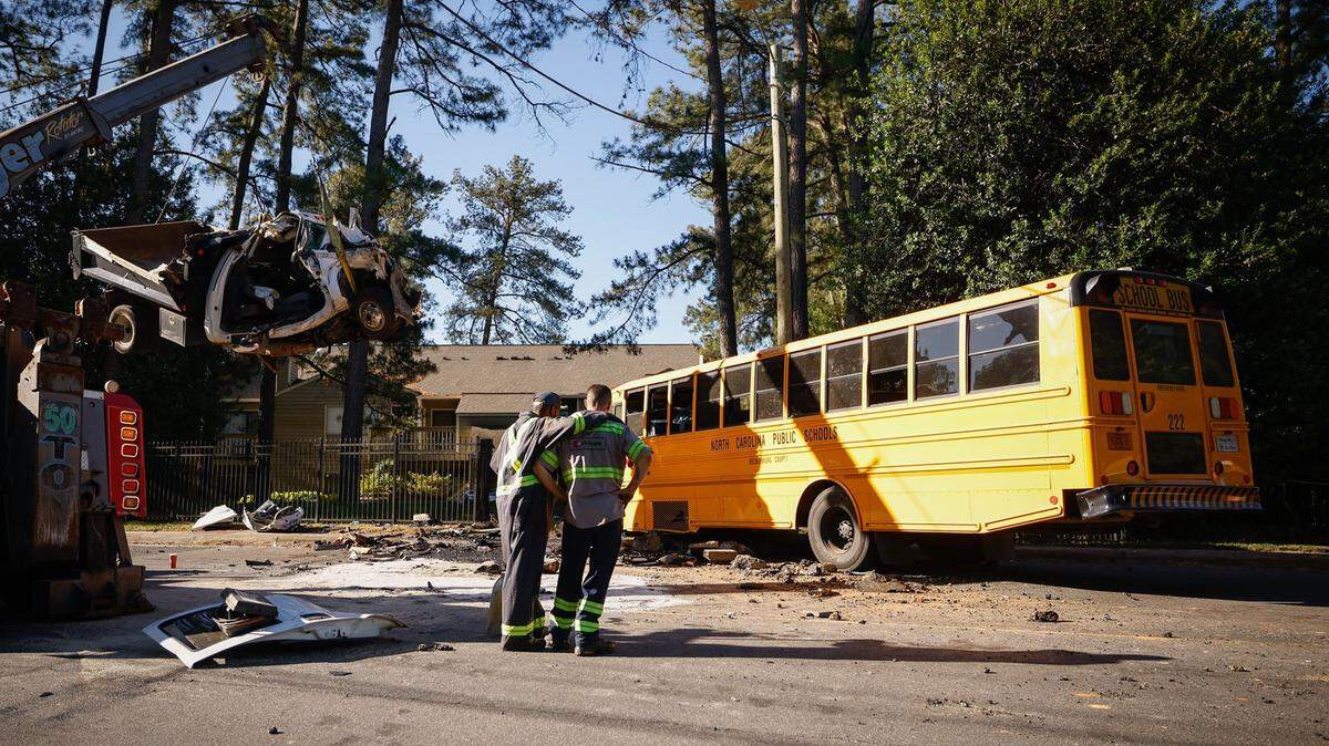Work crews watch as a crane lifts a damaged dump truck from the scene of a wreck with a Charlotte-Mecklenburg Schools bus and another car at Sharonbrook Drive and Sharon Road West on Wednesday May 11, 2022.