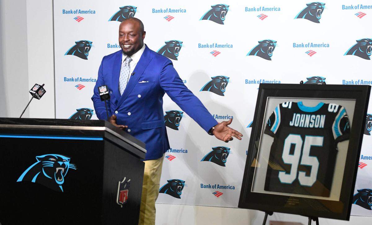 Former Carolina Panthers defensive end Charles Johnson gestures toward his framed No. 95 jersey as he speaks to former teammates and well-wishers during Thursday’s retirement ceremony, which drew dozens of players.