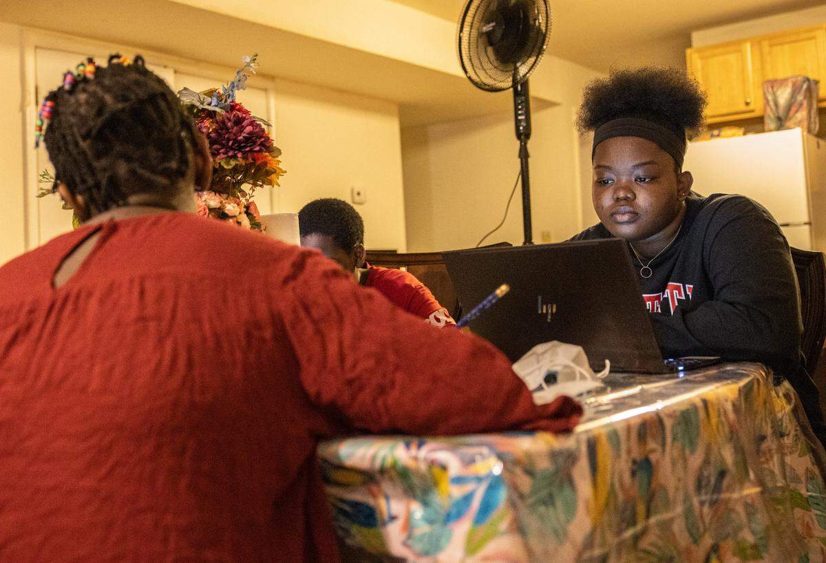Faduma works on homework with her siblings in their Charlotte apartment.