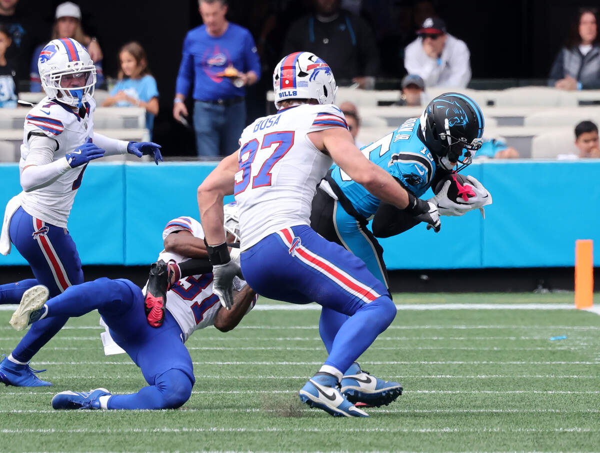 Carolina Panthers' Jimmy Horn Jr. is brought down by Buffalo Bills' Maxwell Hairston (31) and Joey Bosa (97) during Sunday’s game at Bank of America Stadium.