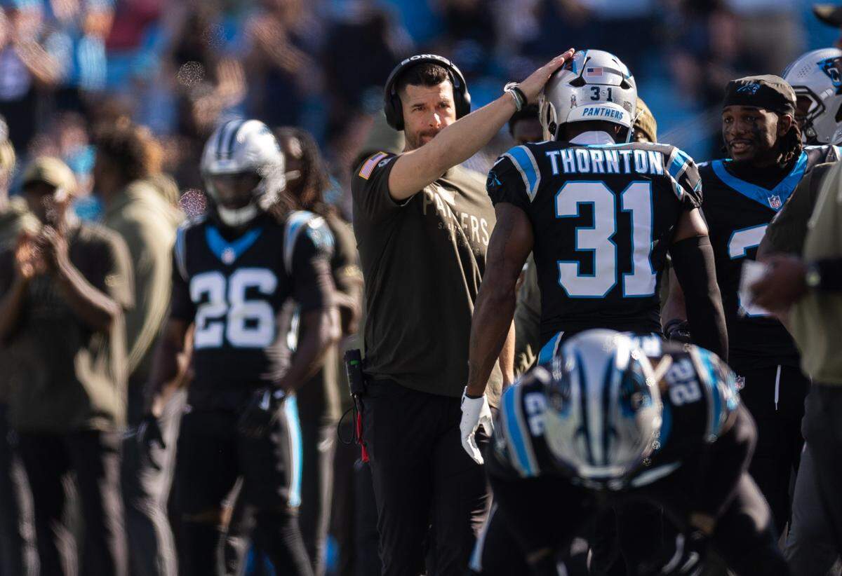 Carolina Panthers coach Dave Canales, left, pats Carolina Panthers cornerback Corey Thornton on the head stands on the sideline sat The Bank of America Stadium in Charlotte, N.C., on Sunday, November 9, 2025.
