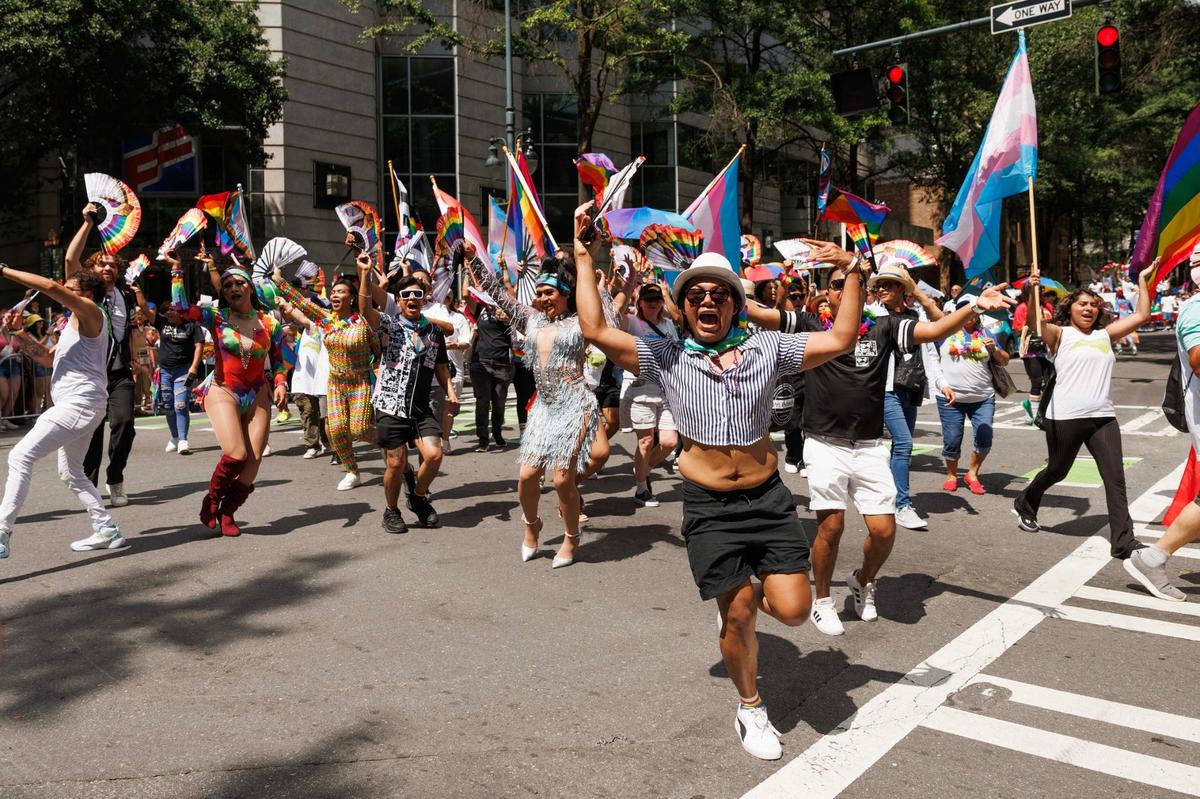 Parade participants representing Equality North Carolina Foundation cheer, jump, and dance through the street during the Charlotte Pride Festival & Parade on Sunday, Aug. 18, 2024