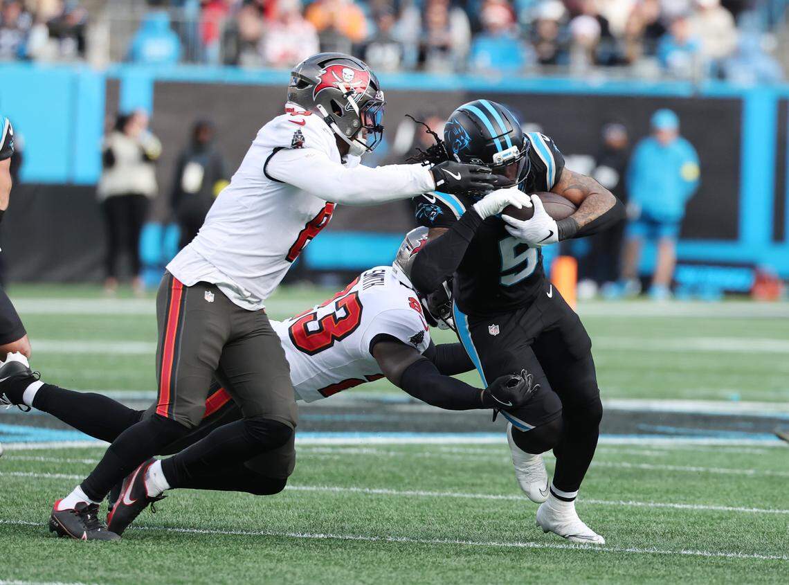 The Panthers' Rico Dowdle carries the ball against the Tampa Bay Buccaneers' SirVocea Donnis, left, and Tykee Smith during the 2025 season in Charlotte.