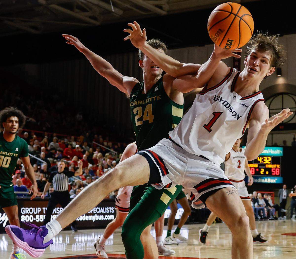 Charlotte’s Rich Rolf, left, tries to knock the ball away from Davidson’s Reed Baily, right, after a rebound during the game at Belk Arena in Davidson on Tuesday, December 10, 2024.