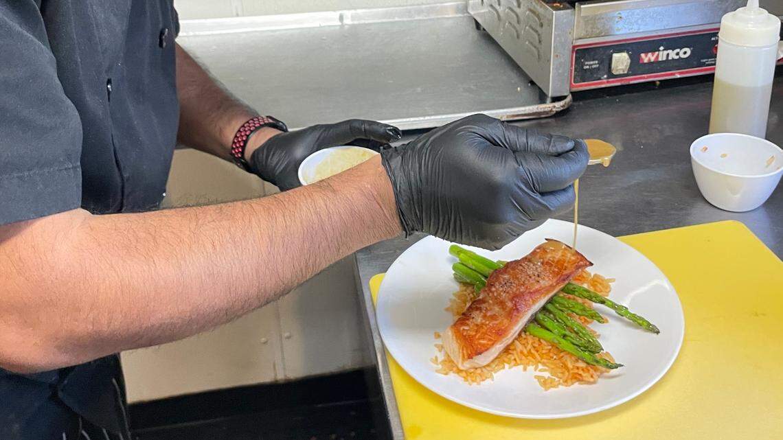 Head chef Victor Carbajal prepares a salmon dish at The Neighborhood Cafe in Huntersville.
