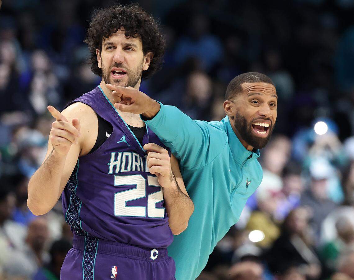 Charlotte Hornets head coach Charles Lee, right, reaches around guard Vasa Micic, left, to give instructions to his team during action against the Dallas Mavericks at Spectrum Center in Charlotte, NC on Monday, January 20, 2025.