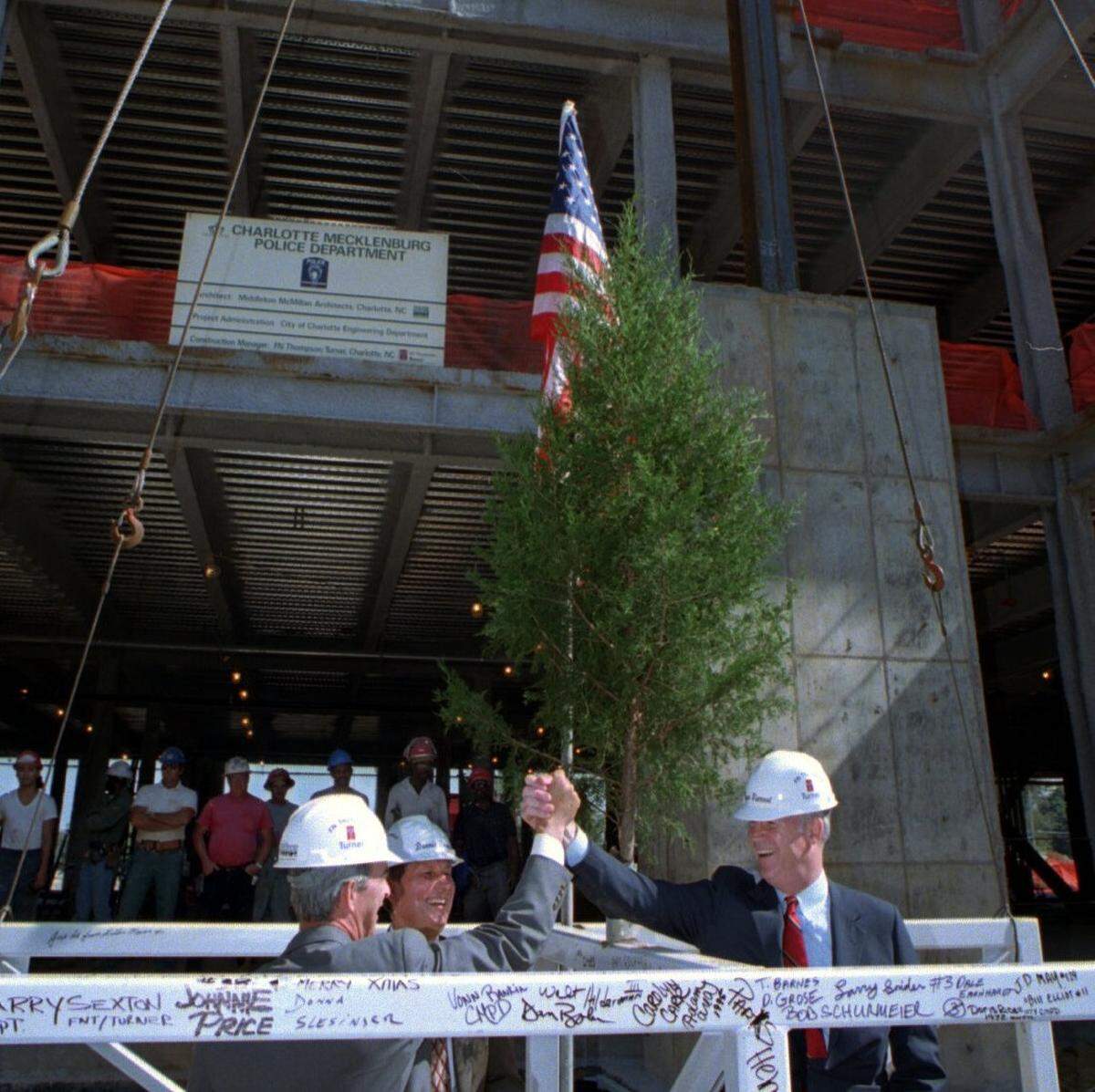 Charlotte Mayor Richard Vinroot (right) and City Manager Wendell White high-five each other after signing a steel beam put in place as part of the topping-off ceremony for the new Charlotte-Mecklenburg Police Department on Oct. 10, 1995.