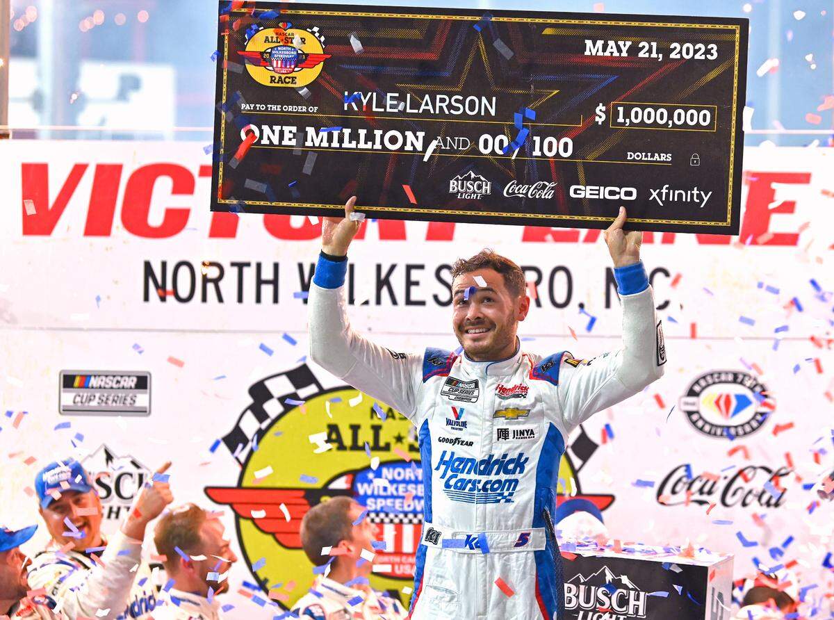 NASCAR driver Kyle Larson glances up at the check he and his team received for winning the NASCAR All-Star race at North Wilkesboro Speedway on Sunday, May 21, 2023.