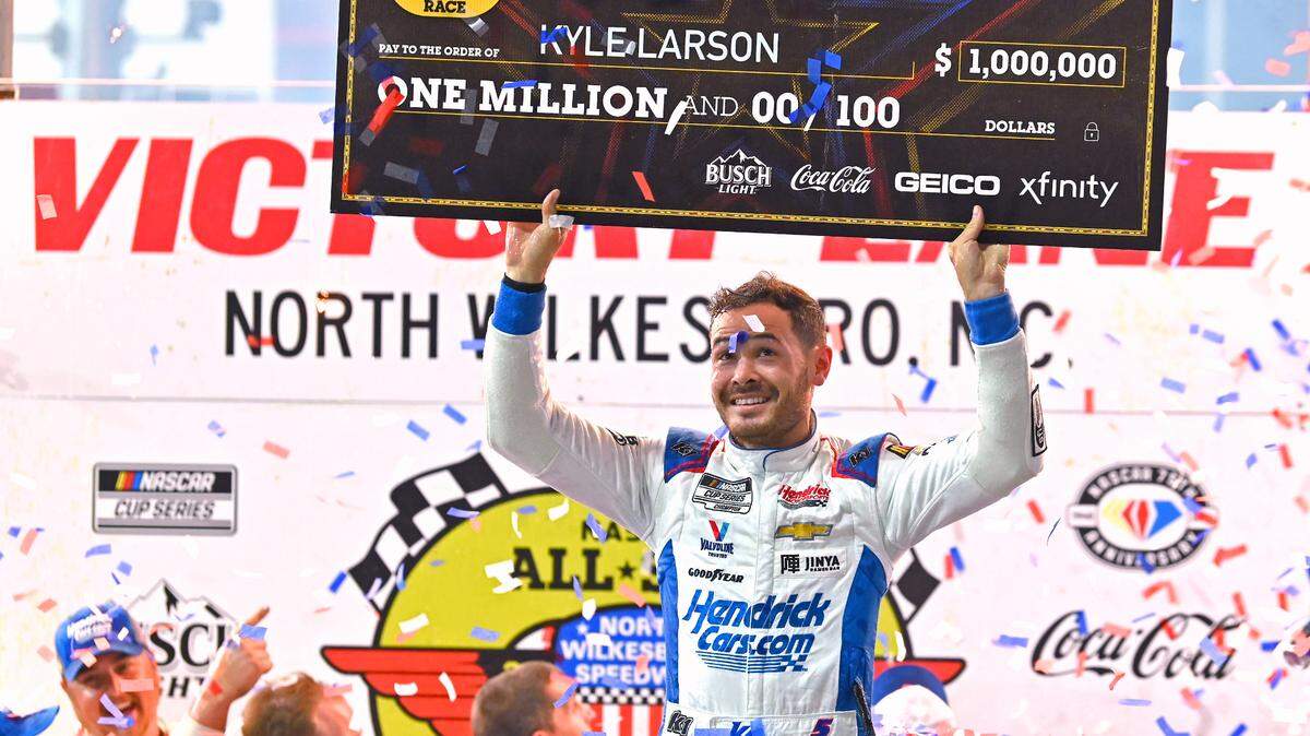 NASCAR driver Kyle Larson glances up at the check he and his team received for winning the NASCAR All-Star race at North Wilkesboro Speedway on Sunday, May 21, 2023.