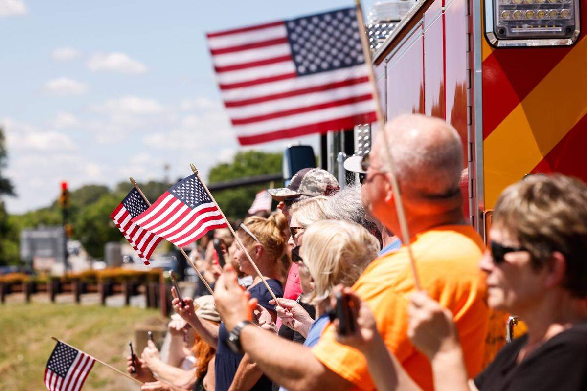 Spectators wave American flags on the bridge at exit 28 for Deputy U.S. Marshal Thomas “Tommy” Weeks Jr. processional on I-77 on Wednesday, May 1, 2024. Weeks, a 48-year Mooresville father of four, died in Monday’s Charlotte shooting where four law enforcement officers died and four more wounded.