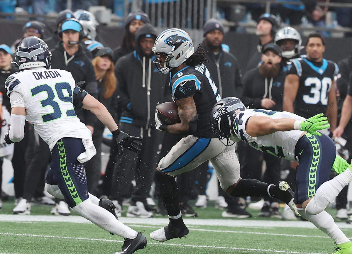 Carolina Panthers running back Rico Dowdle, center, carries the ball before being tackled as Seattle Seahawks Ty Okada (39) and Drake Thomas, right, apply pressure during their Dec. 28, 2025 game at Bank of America Stadium in Charlotte.