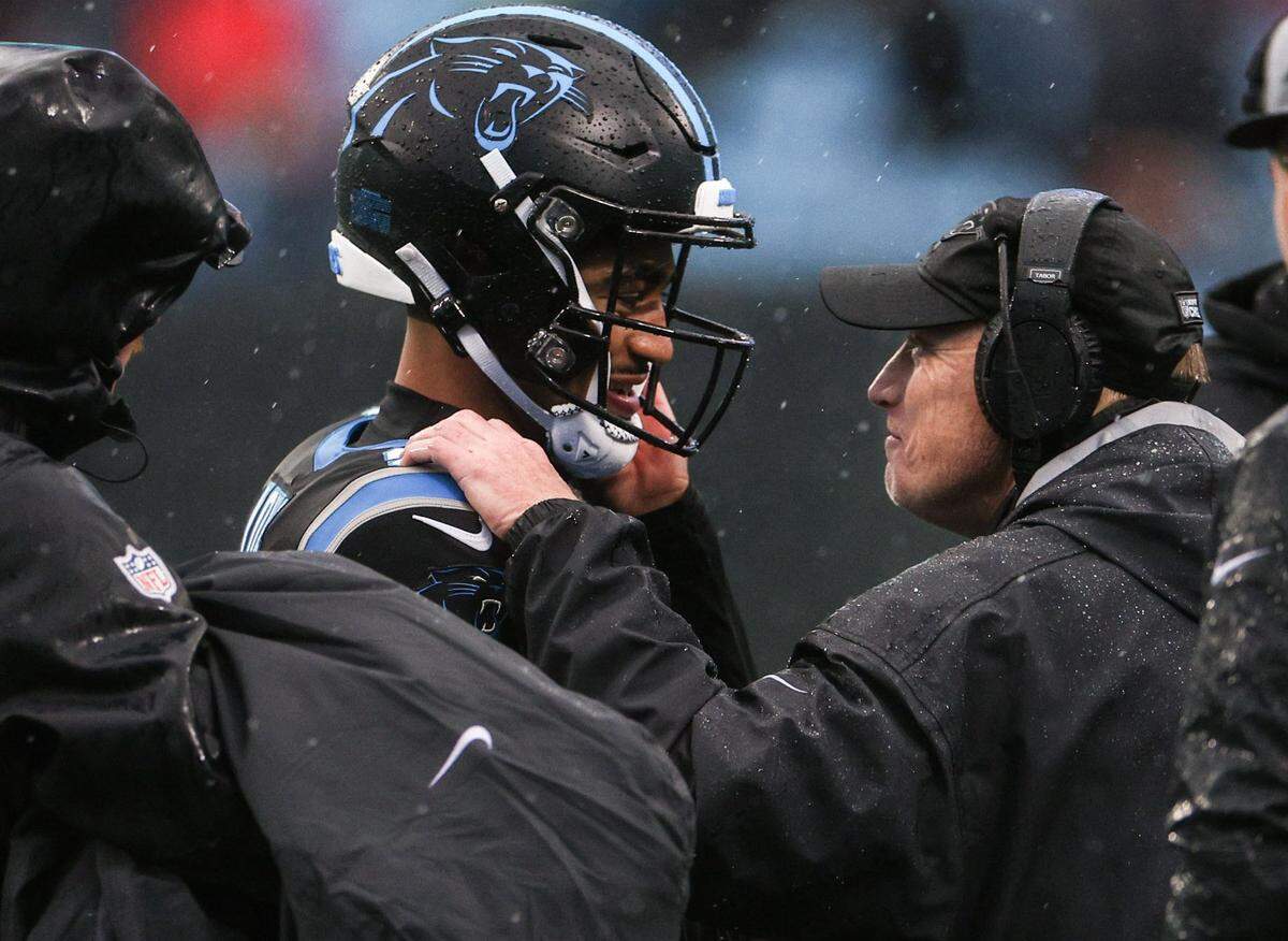 Panthers quarterback Bryce Young, second from left, and interim head coach Chris Tabor, share a moment during a timeout during the game against the Falcons at Bank of America Stadium on Sunday, December 16, 2023.