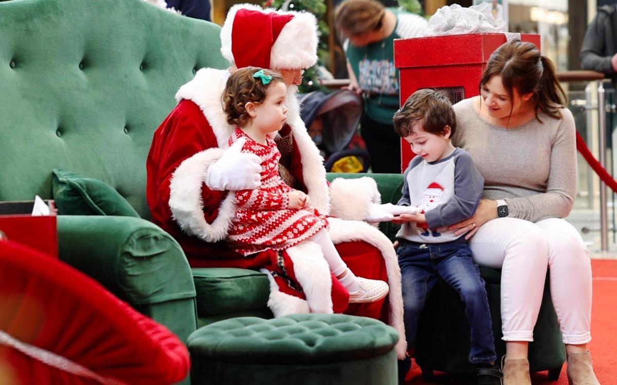 Cecilia Veiga, Leo Veiga and Ashley Veiga get seated next to Santa Claus during the Caring Santa event at the SouthPark Mall in Charlotte, NC on Sunday, December 4, 2022. The event is for children with disabilities and are adversely affected by high sensory events such as a loud, busy mall. The Caring Santa event was hosted before regular mall hours.