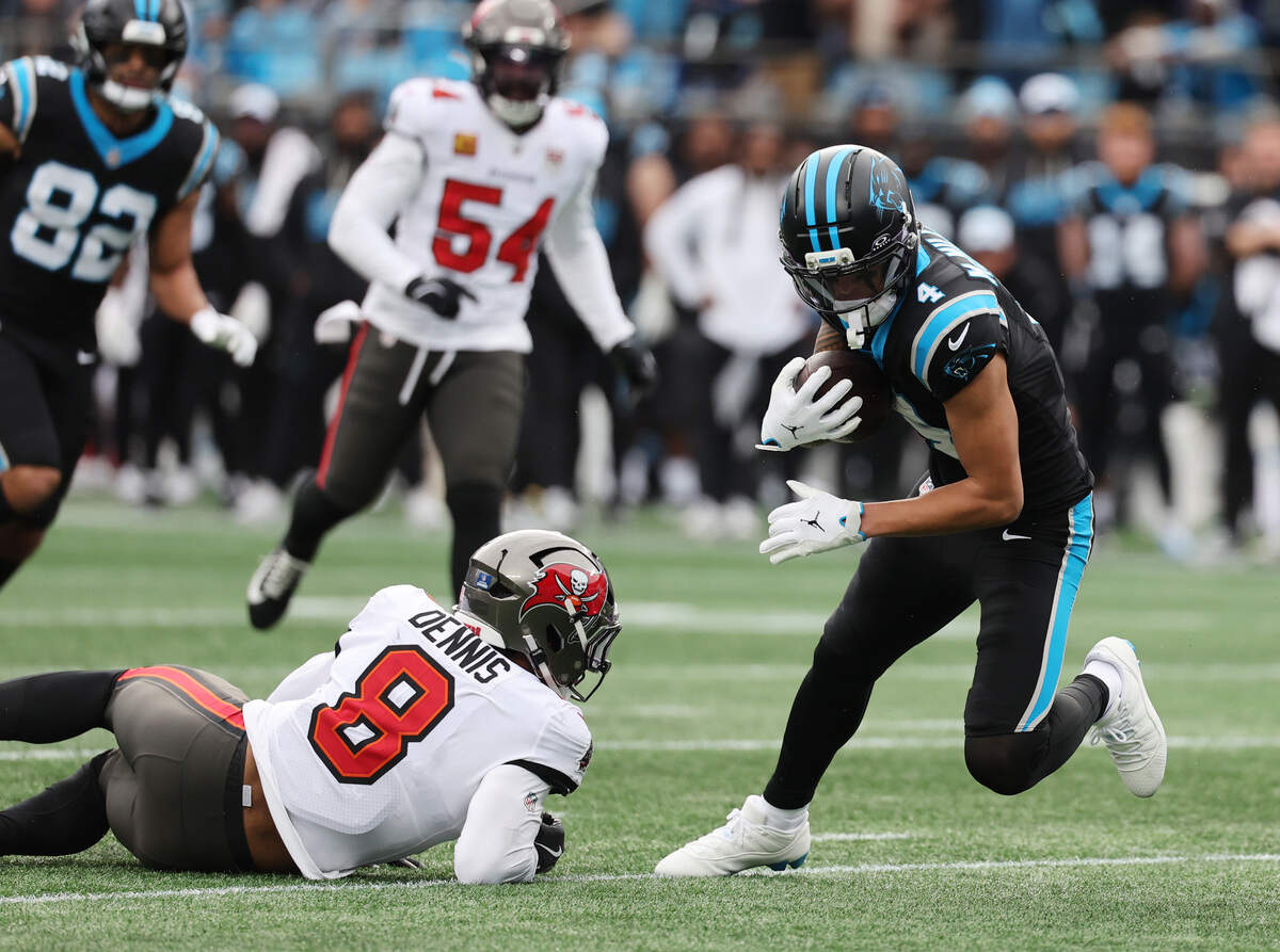 Carolina receiver Tetairoa McMillian carries the ball as Tampa Bay’s SirVocea Dennis dives for the tackle Sunday at Bank of America Stadium in Charlotte.