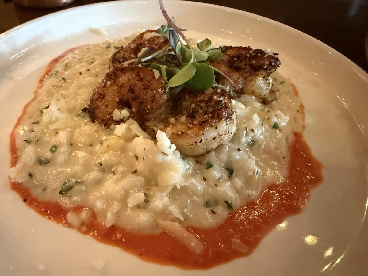 Seared shrimp served over a bed of white risotto with a drizzle of red pepper sauce.