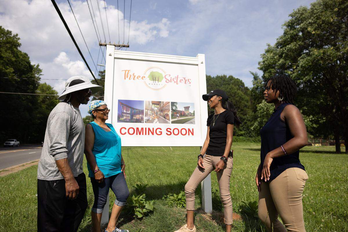 Members of the West Boulevard Neighborhood Coalition pose for a portrait next to a sign for the future Three Sisters grocery store. Wells Fargo is donating money to the project, part of $6 million that it is giving to nonprofits working in West Charlotte.
