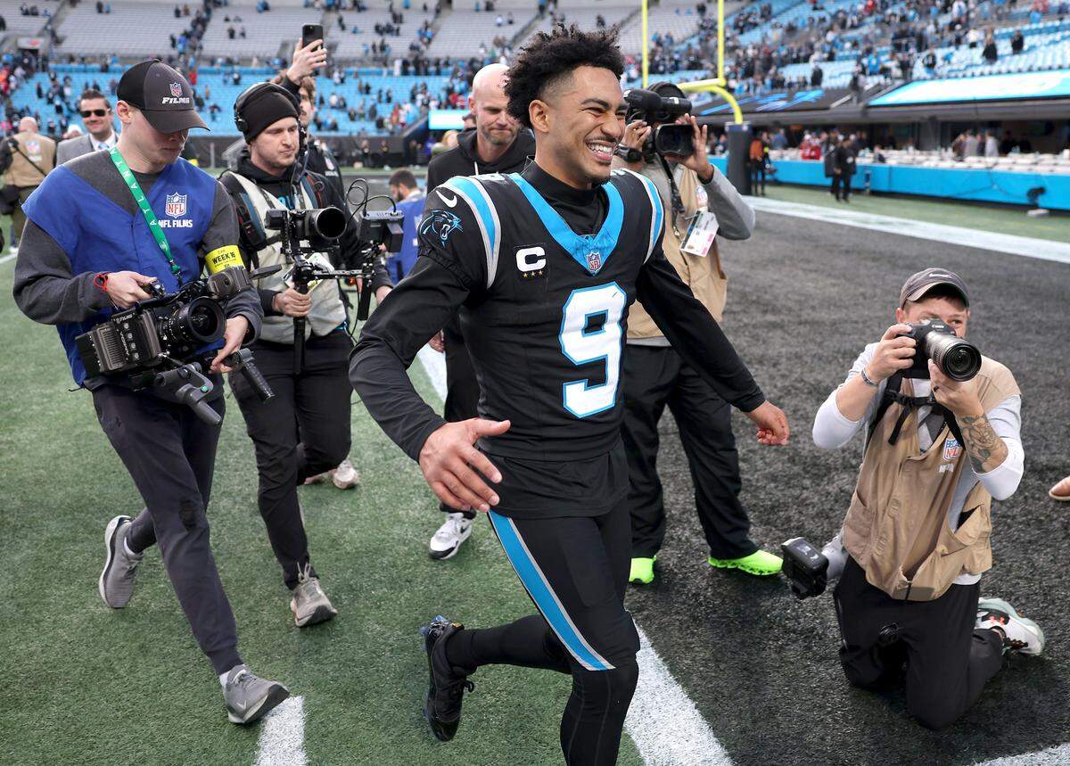 Carolina Panthers quarterback Bryce Young runs off the field smiling to head coach Dave Canales following the team's 23-20 victory over the Tampa Bay Buccaneers on Sunday, December 21, 2025 at Bank of America Stadium in Charlotte, NC.