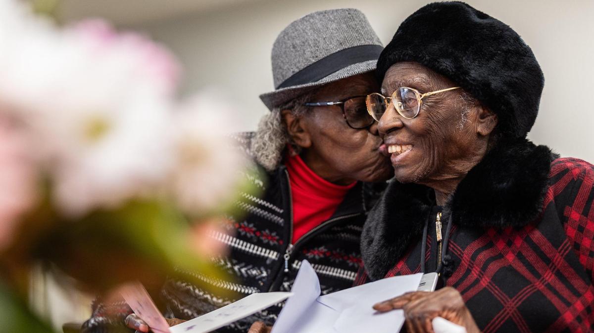 Julia Ann Teamer, right, gets a birthday kiss from her next door neighbor, Zedia Williams, during her 108th birthday at her retirement community in Charlotte, N.C., on Thursday, January 16, 2025.