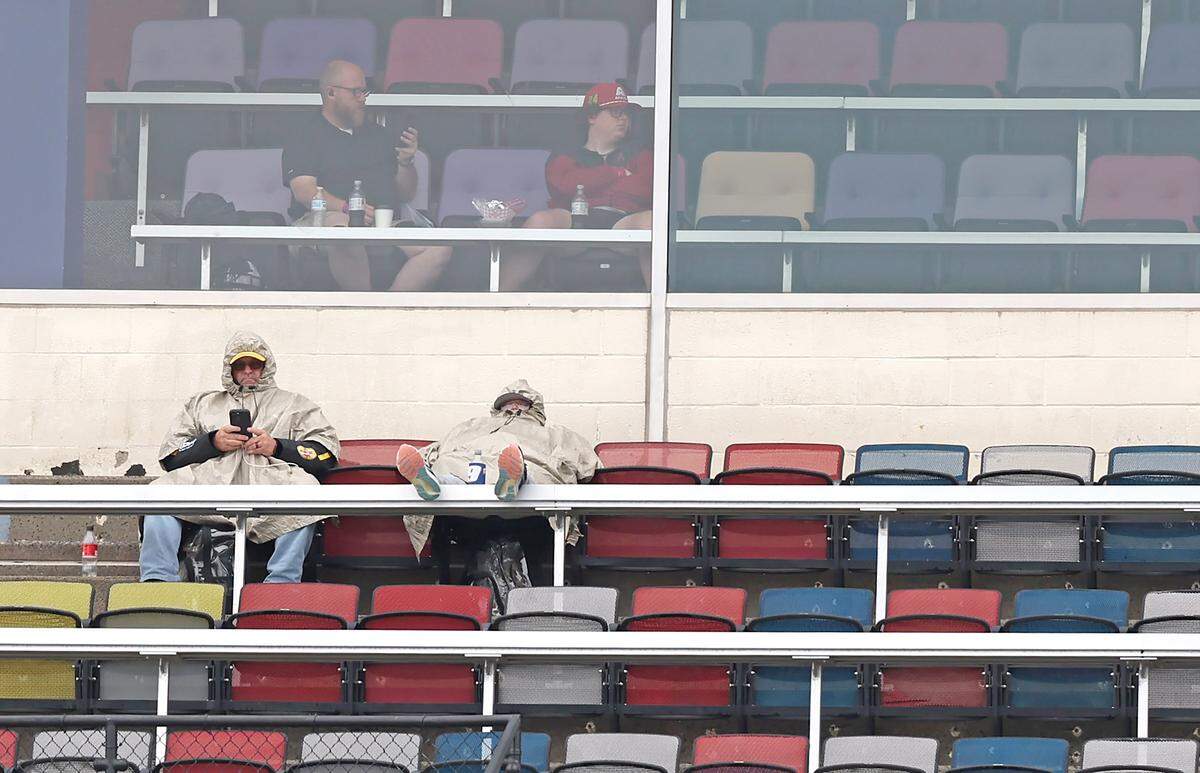 NASCAR fans sit in two realms of comfort on Saturday at Charlotte Motor Speedway in Concord, NC. Rain has canceled the NASCAR Cup Series practice and qualifying for the day. 