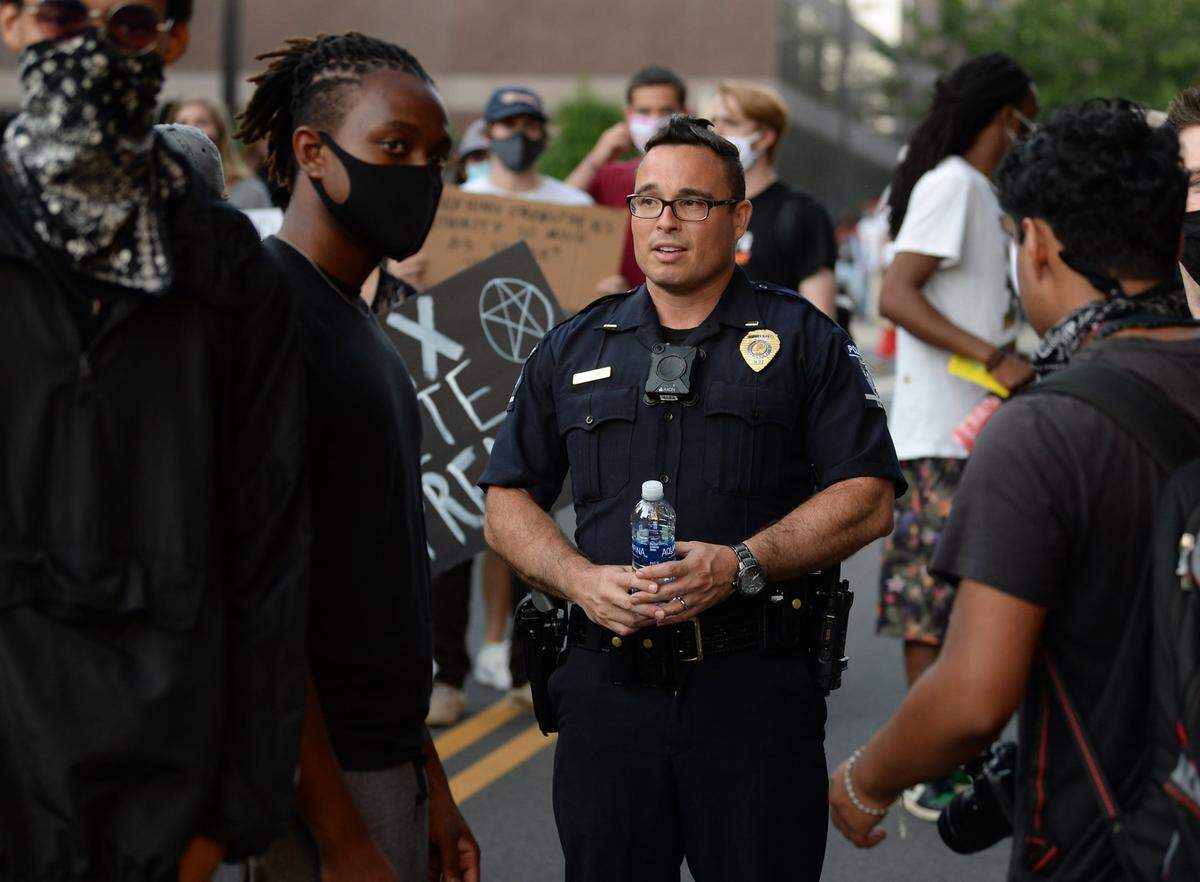 Charlotte-Mecklenburg Police Officer S.A. Fischbach, center, speaks with demonstrators outside the Charlotte-Mecklenburg Government Center in uptown Charlotte on June 2, 2020. The demonstrators were protesting the death of George Floyd and others killed by police.