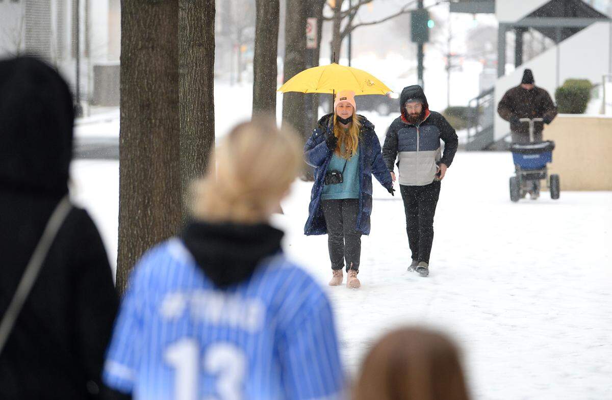 Brooke Gautreaux, left and her husband, Caray, right, walk along Stonewall Street as a wintry mix of rain, sleet and snow fall on Sunday, January 16, 2022.