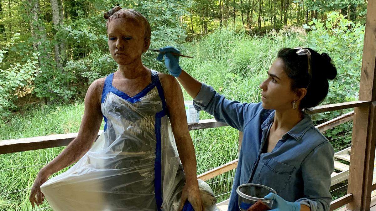 Cristina Córdova at work on the porch of her Penland, N.C., studio in August. She was working on a sculpture of her daughter that is now part of her “Cuerpo Exquisito” exhibition at Hodges Taylor gallery in Charlotte.