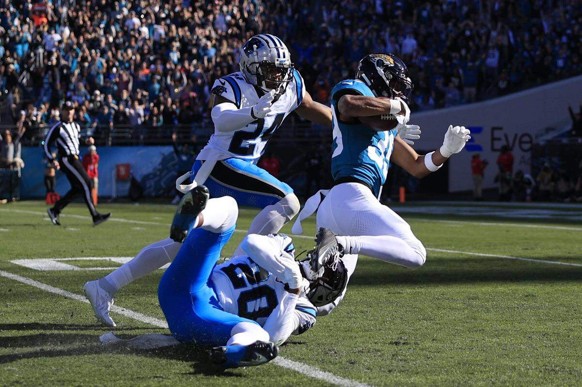 Jacksonville Jaguars wide receiver Jamal Agnew (39) rushes for yards as he is tackled by Carolina Panthers cornerback Shaquill Griffin (20) and safety Vonn Bell (24) during the second quarter of a regular season NFL football matchup Sunday, Dec. 31, 2023 at EverBank Stadium in Jacksonville, Fla.