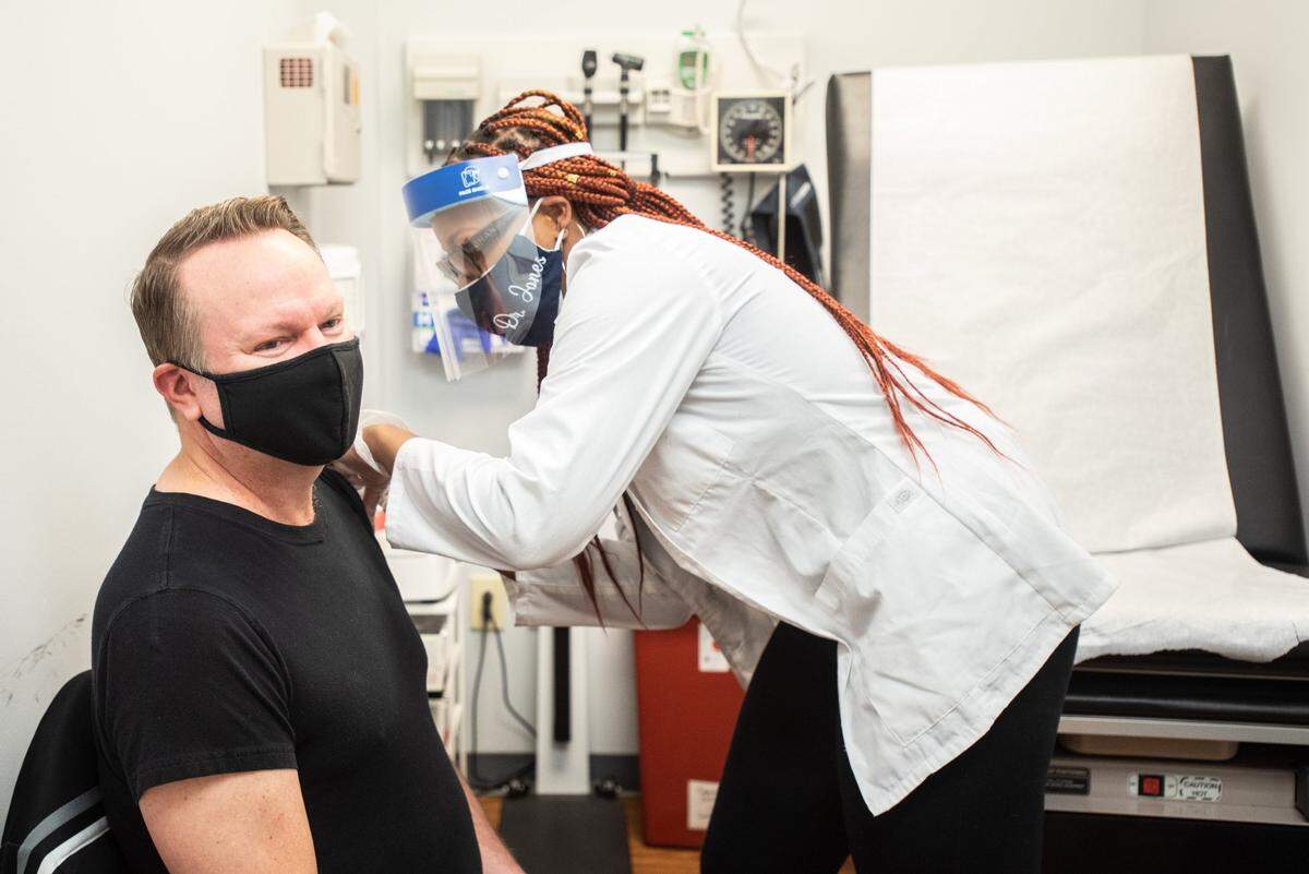 Mark Burleson (left) Is administered the COVID-19 vaccine by Dr. Jaelyn Jones at Premier Pharmacy And Wellness Center in Charlotte, NC, on Thursday, March 18, 2021.
