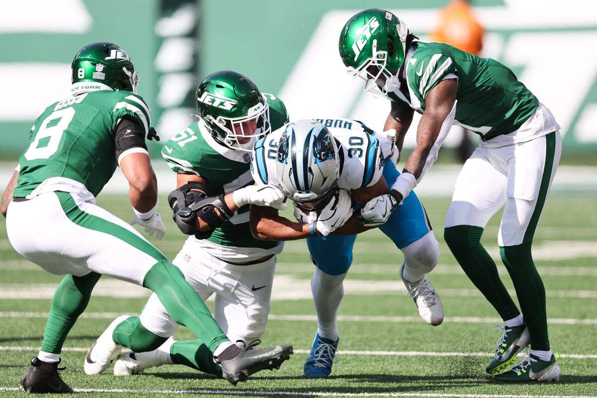 Carolina Panthers running back Chuba Hubbard (30) is tackled by New York Jets linebacker Kiko Mauigoa (51) and cornerback Sauce Gardner (1) in the second quarter on Sunday in New Jersey.