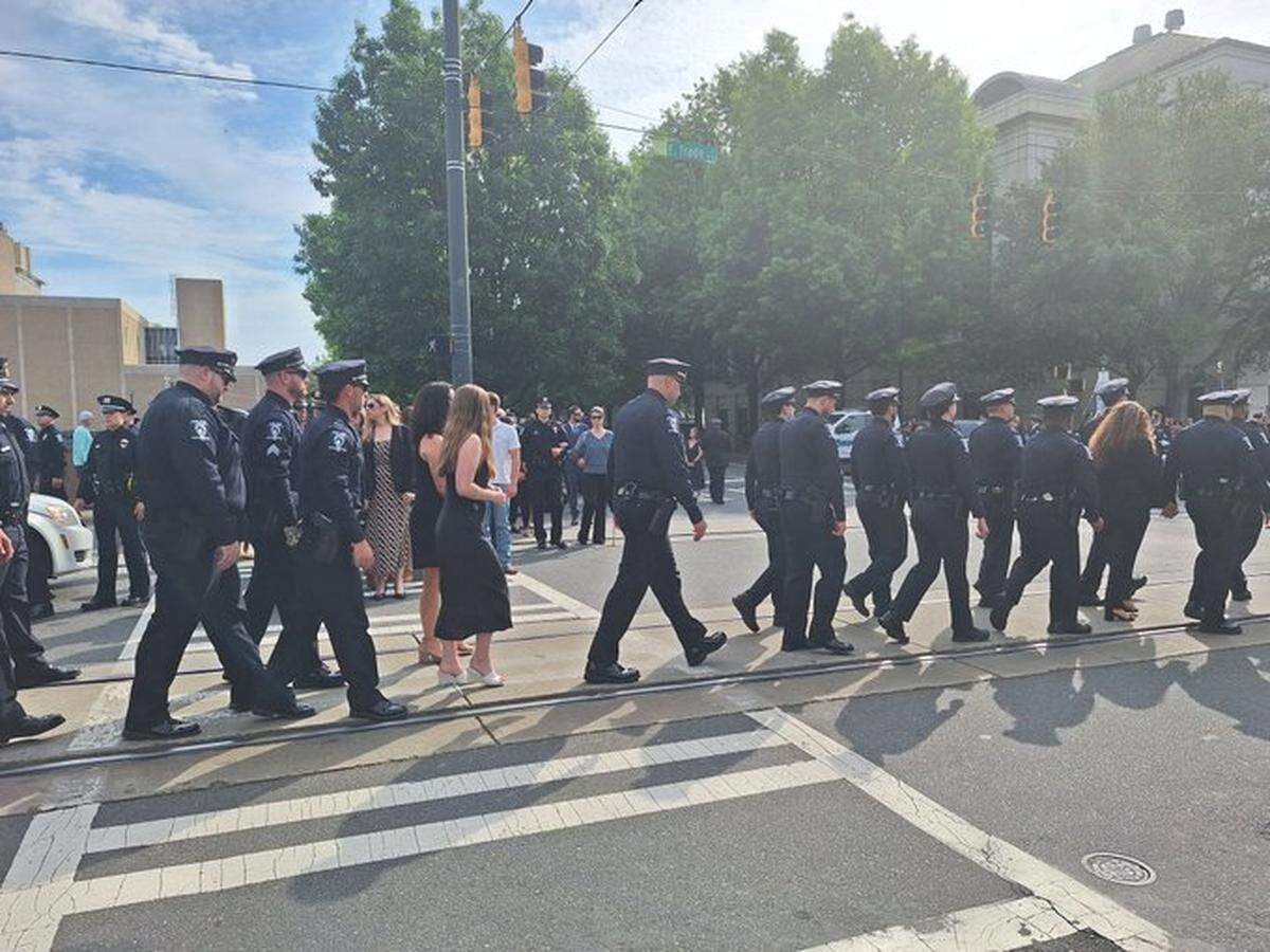 CMPD officers and others walk during Joshua Eyer processional, Friday, May 3, 2024.