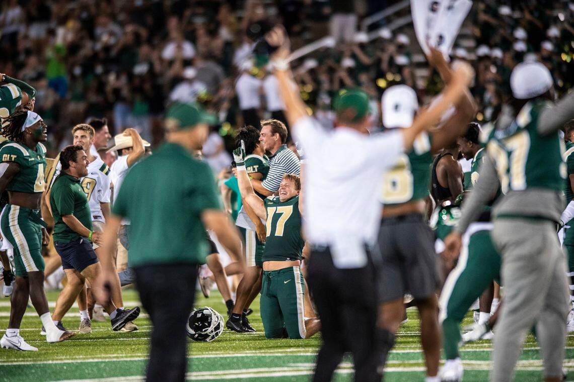 Charlotte 49ers players, coaches and fans rush the field after Charlotte beat Duke, 31-28, at Jerry Richardson Stadium on Friday.