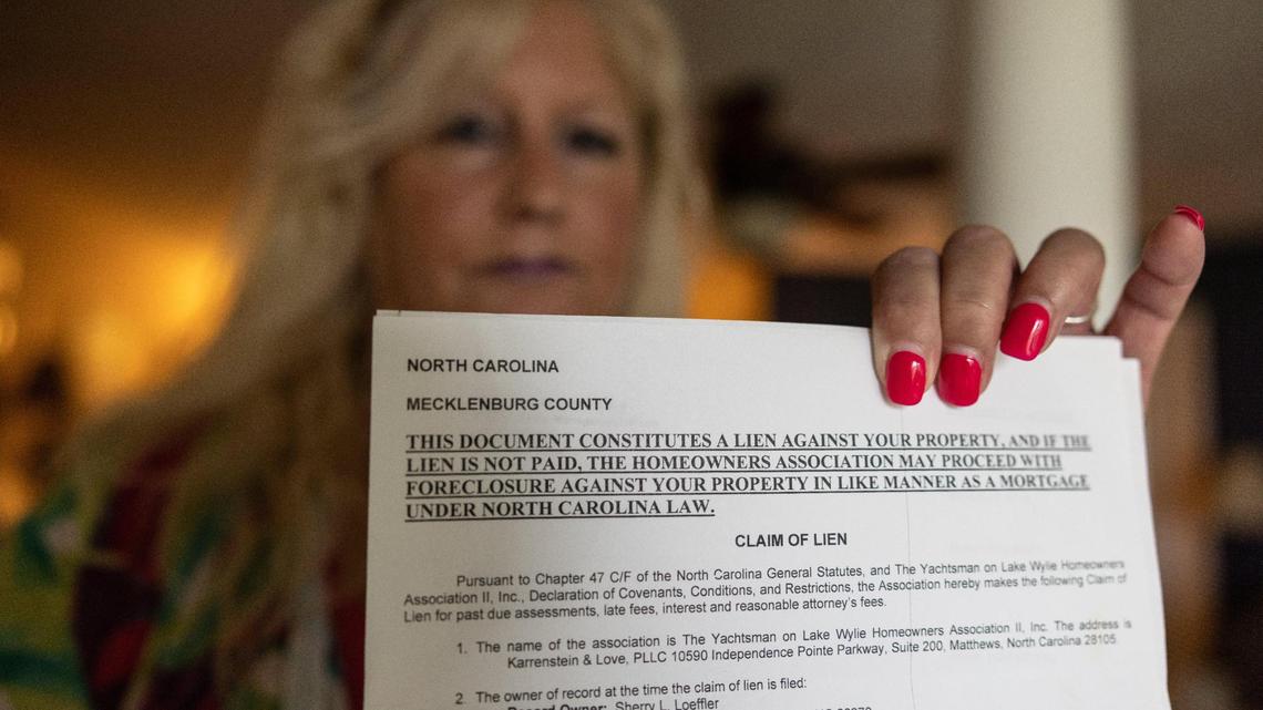 Sherry Loeffler holds the notice of the lien that her HOA put on her home after fining her nearly $12,000 over windows that she contends it approved. A Mecklenburg County judge ordered the HOA to remove the lien.
