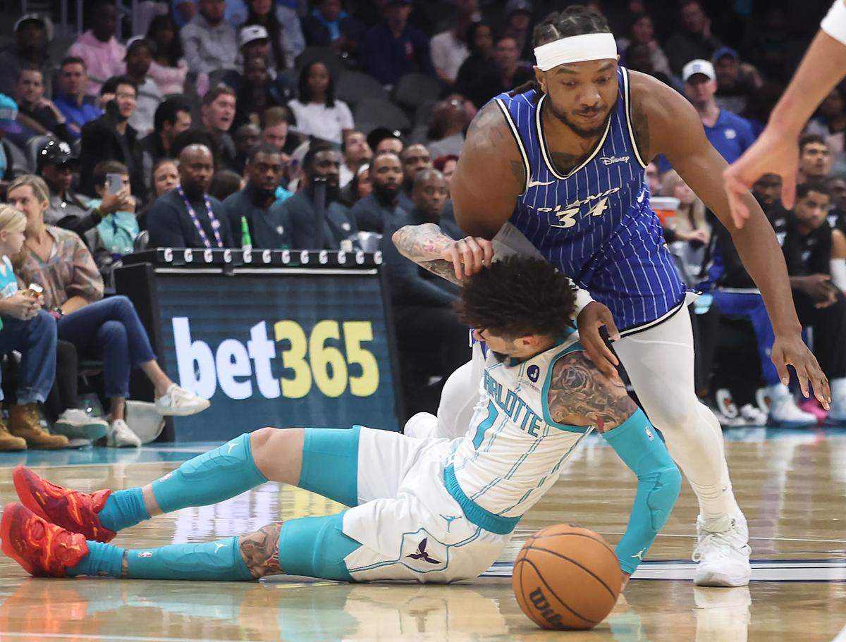 Charlotte Hornets guard LaMelo Ball, left, falls to the court as Orlando Magic center Wendell Carter Jr., right, goes after the loose ball during action at Spectrum Center in Charlotte, NC on Thursday, October 30, 2025.