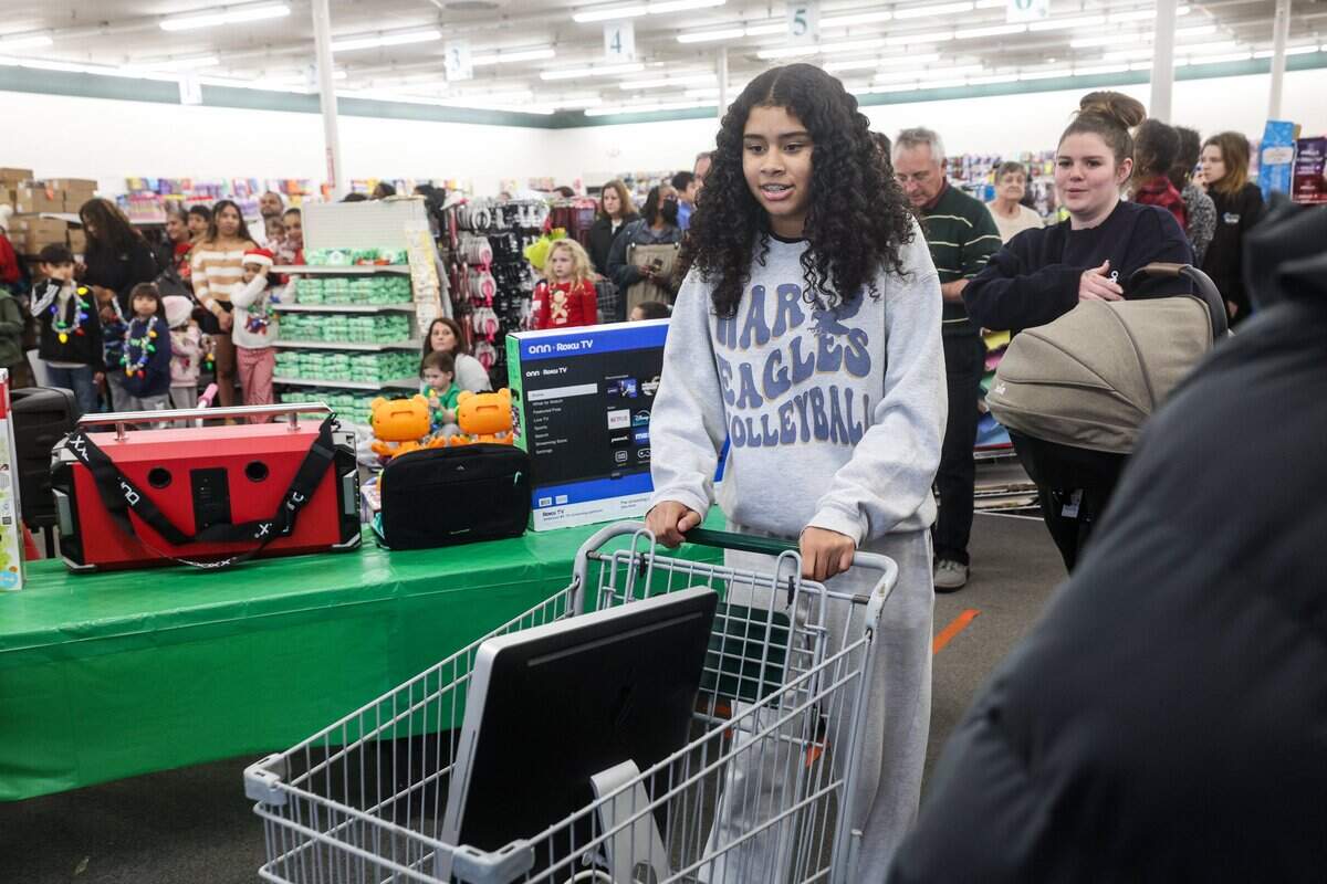 Anna Burch, 13, wheels a brand new Apple desktop computer after winning a raffle during “secret santa” gift giveaway at Might Dollar store in Gastonia, NC on Friday, December 12, 2025. Joe Mayes, a local Gastonia resident and radio personality on Gaston College's WSGE, teamed up with his friend and fillmaker, Tim Greene, to buy gifts ranging from smart TVs and computers, to toys and bikes.